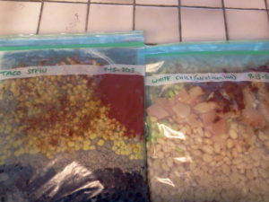 Two flattened gallon bags with meals in them to be frozen.